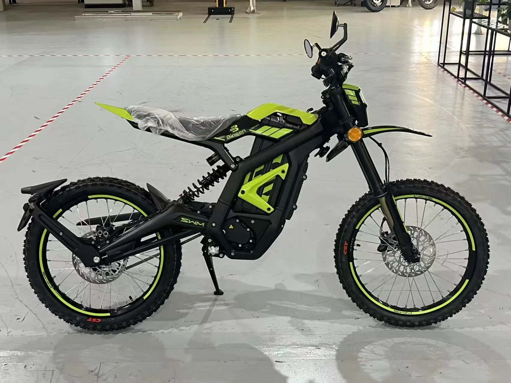 Black electric bike with green accents on a gray floor