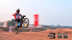 Motorcycle rider on a dirt track with 'Binsen' branding.