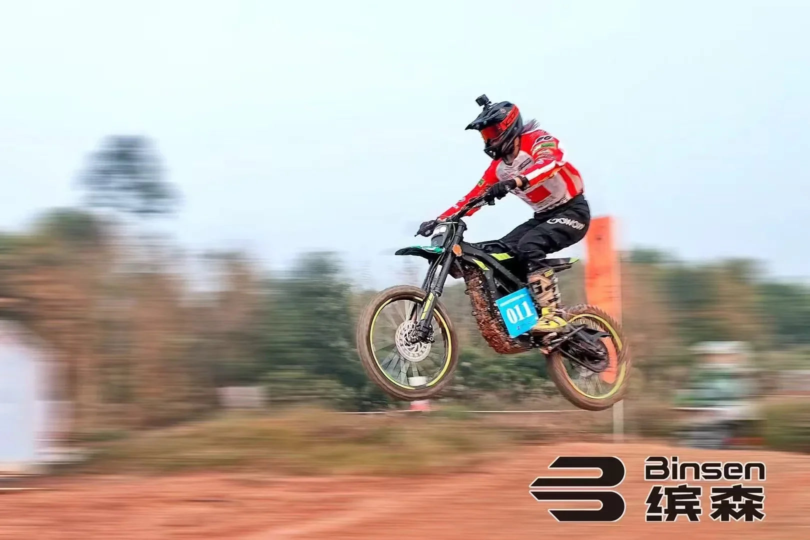 Biker in mid-air on a dirt bike with Binsen logo in the background