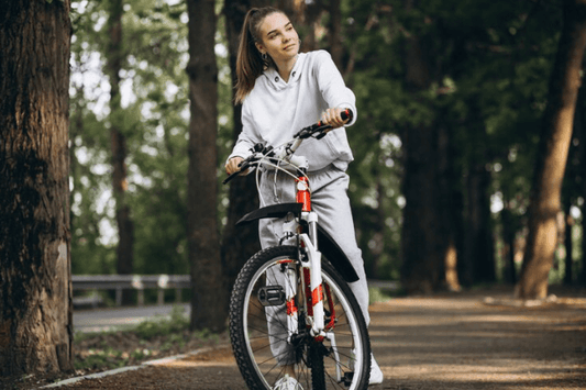 Woman with red and white electric bike on forest trail, side front view