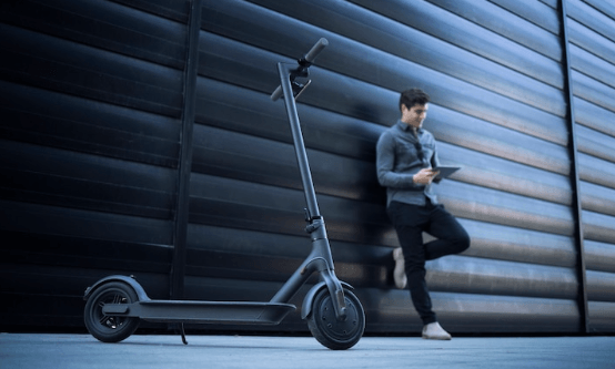 black electric scooter side view in urban setting with person leaning against wall
