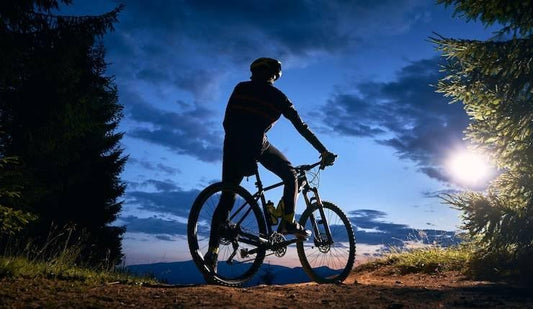 Electric mountain bike side view on a forest trail at dusk with rider silhouetted