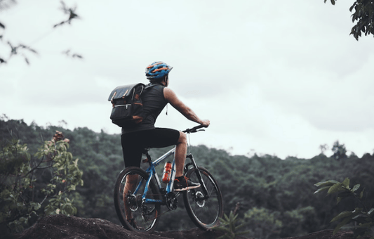 Electric bike in use outdoors, side view, rider on forest trail with backpack and helmet