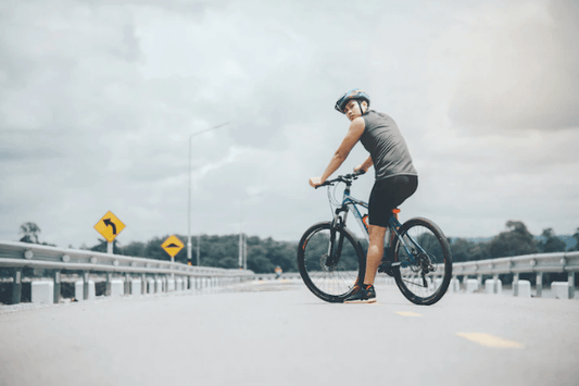 Electric bike in matte black with rider, side view, on an open road outdoors
